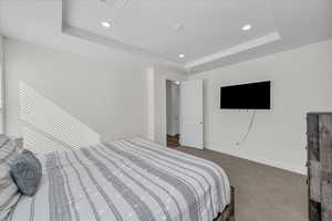 Bedroom with carpet, baseboards, a raised ceiling, and recessed lighting