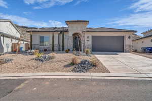 View of front of house with an attached garage, stone siding, concrete driveway, and stucco siding