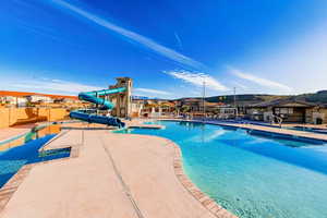 Community pool with a patio, a water slide, and fence