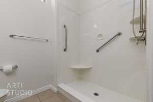 Bathroom featuring tile patterned flooring, a shower, baseboards, and toilet