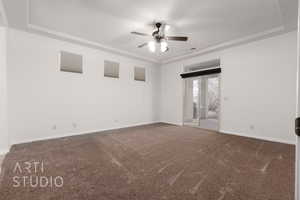 Empty room with carpet flooring, ceiling fan, baseboards, and a tray ceiling