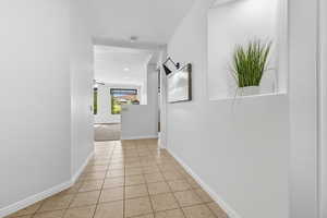 Hallway featuring baseboards and light tile patterned flooring