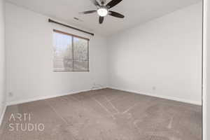Carpeted spare room with a ceiling fan and baseboards