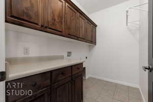 Washroom with cabinet space, washer hookup, baseboards, light tile patterned floors, and electric dryer hookup