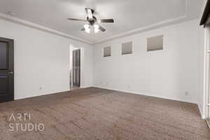 Carpeted empty room with ceiling fan, baseboards, a tray ceiling, and a smoke detector