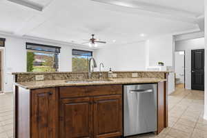 Kitchen featuring light tile patterned flooring, dishwasher, an island with sink, a ceiling fan, and light stone countertops