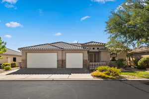 View of front of house with concrete driveway, an attached garage, stucco siding, stone siding, and a tiled roof