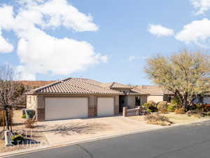 Mediterranean / spanish house featuring stucco siding, an attached garage, a tile roof, stone siding, and concrete driveway