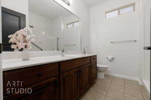 Bathroom featuring vanity, toilet, baseboards, tile patterned flooring, and a shower