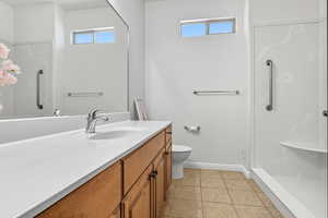 Bathroom with plenty of natural light, vanity, a stall shower, and light tile patterned floors