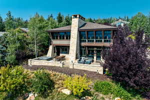 Back of house featuring a hot tub, a sunroom, outdoor lounge area, and a patio area