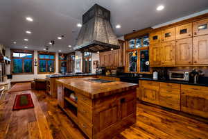 Kitchen featuring butcher block countertops, a kitchen island, dark hardwood / wood-style floors, stainless steel gas cooktop, and island exhaust hood