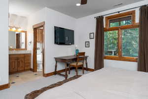 Tiled bedroom with ceiling fan, ensuite bathroom, and sink