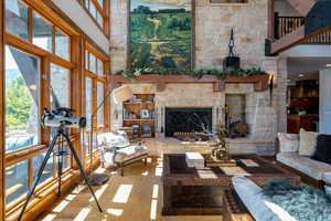 Living room featuring a stone fireplace and a towering ceiling