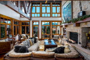 Living room with a healthy amount of sunlight, a stone fireplace, and a high ceiling