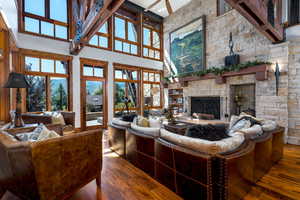 Living room featuring a stone fireplace, a towering ceiling, and dark wood-type flooring