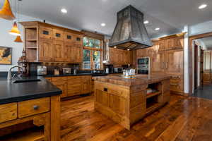 Kitchen featuring island exhaust hood, a center island, sink, and black microwave