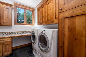 Laundry area with cabinets, washer and clothes dryer, and dark tile patterned flooring