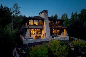 Back house at dusk featuring an outdoor living space, a balcony, and a patio area