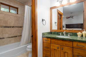 Full bathroom with shower / bath combination with curtain, vanity, ceiling fan, toilet, and tile patterned floors