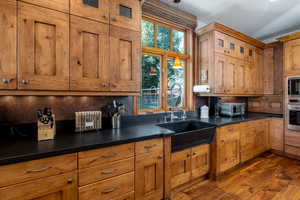 Kitchen with built in microwave, sink, stainless steel oven, dark hardwood / wood-style flooring, and backsplash