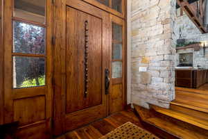 Entrance foyer with hardwood / wood-style flooring, plenty of natural light, and a stone fireplace