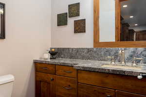 Bathroom featuring vanity, backsplash, and toilet