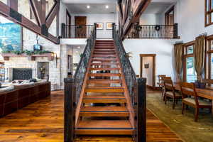 Stairway featuring wood-type flooring, a fireplace, and a high ceiling