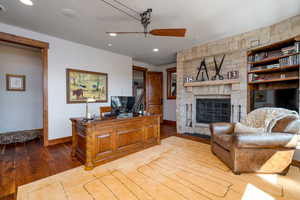 Living room featuring a fireplace, light hardwood / wood-style floors, and ceiling fan