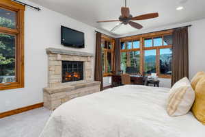 Bedroom featuring multiple windows, a stone fireplace, and carpet flooring