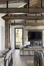 Living room with a glass covered fireplace, vaulted ceiling with beams, and light wood-style flooring