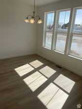 Spare room featuring baseboards, dark wood finished floors, visible vents, and a notable chandelier