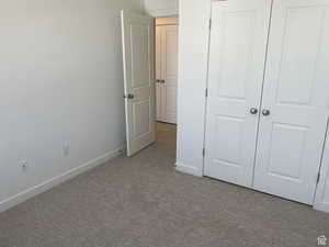 Unfurnished bedroom with light carpet and baseboards