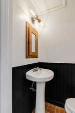 Bathroom with brick floor, wainscoting, and toilet