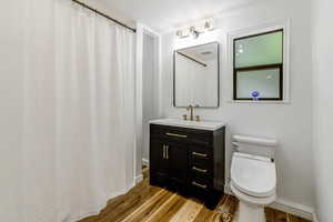 Full bath featuring toilet, baseboards, wood finished floors, and vanity