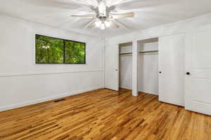Unfurnished bedroom with light wood finished floors, crown molding, visible vents, and multiple closets