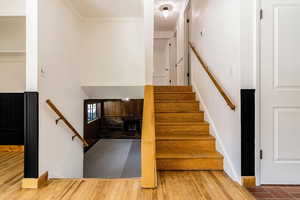 Stairway with crown molding and wood finished floors