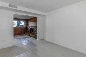 Unfurnished living room with light carpet, baseboards, visible vents, and a fireplace with raised hearth