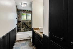 Bathroom featuring a wainscoted wall,  shower combination, toilet, and vanity
