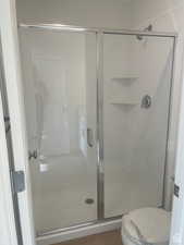 Full bath with a stall shower, wood finished floors, and toilet