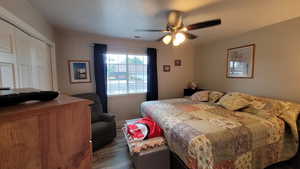 Bedroom featuring dark wood-type flooring, a closet, visible vents, and a ceiling fan