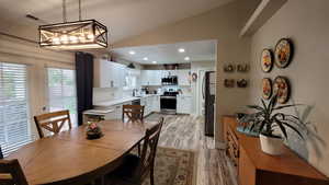 Dining space with vaulted ceiling, recessed lighting, visible vents, and light wood-style floors