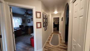 Hallway with dark wood-style floors, baseboards, and arched walkways