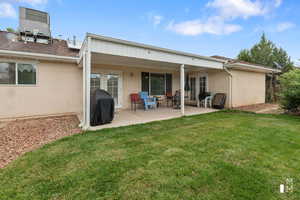 Back of property with french doors, a lawn, central AC unit, and stucco siding