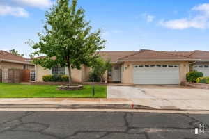 View of front of house featuring a tile roof, stucco siding, a garage, driveway, and a front lawn