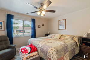 Bedroom with visible vents, a ceiling fan, a textured ceiling, wood finished floors, and baseboards