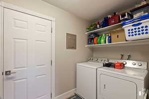 Clothes washing area featuring laundry area, electric panel, baseboards, washer and dryer, and a textured ceiling