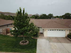 Ranch-style home with a tile roof, a mountain view, a front lawn, and concrete driveway