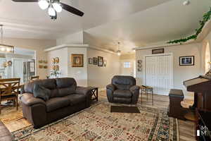 Living room featuring lofted ceiling, baseboards, a ceiling fan, and wood finished floors