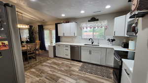 Kitchen featuring stainless steel appliances, a sink, light countertops, and white cabinetry